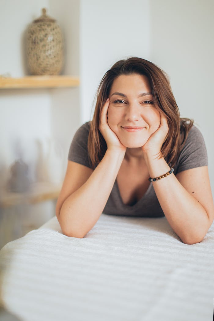 about-us Woman smiling indoors, enjoying a relaxing spa day with a happy expression.