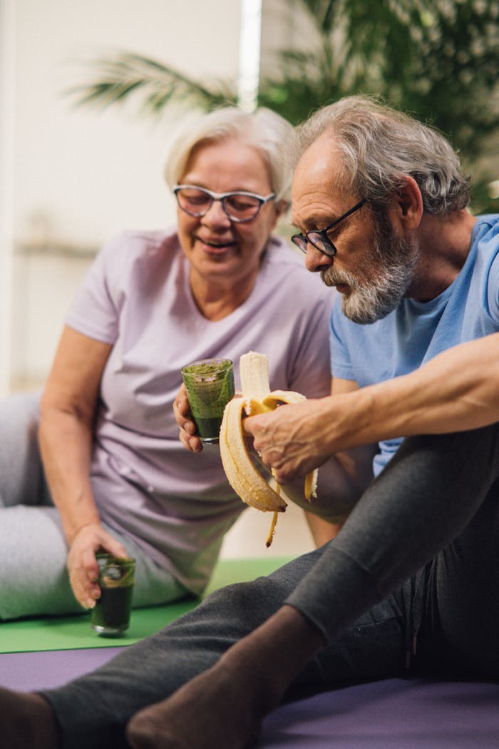 services-05 Elderly man and woman sharing a healthy snack while relaxing indoors, promoting a healthy lifestyle.